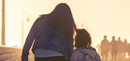 Mamma och barn går mot sol